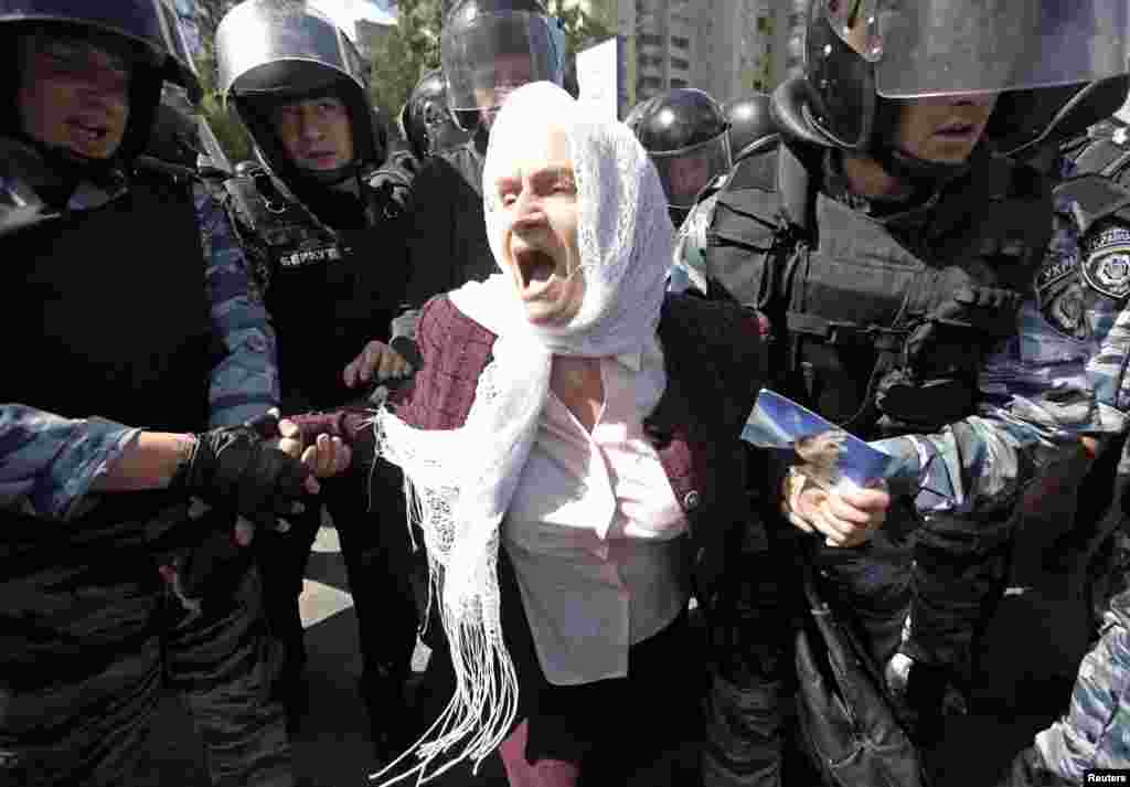 Ukrainian riot police detain an elderly Orthodox Christian activist as she protests against the gay-pride parade.&nbsp;