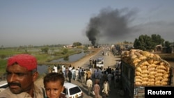 Passengers sat on the roof of a bus near burning oil tankers that were attacked by militants on October 1 near Shikarpur, Pakistan.