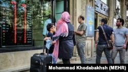 Iranian travelers stand in front of a currency exchange in Tehran, hoping to exchange money on April 11.