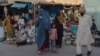 A burqa-clad Afghan woman looks for items to buy at a shop displaying used household items for sale at a market area in Kabul.