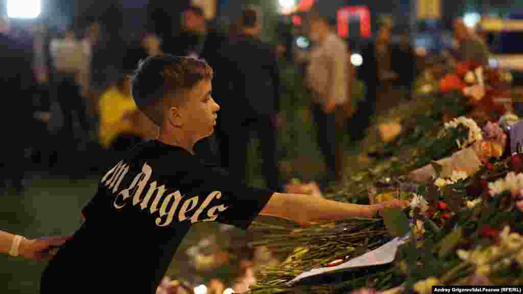 A boy puts flowers at the memorial site in Kazan.