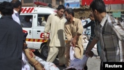 Volunteers carry a victim to an ambulance from the site of a suicide attack during a Shi'ite procession in Quetta.