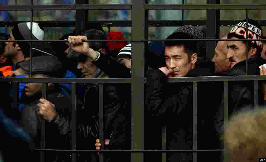 Migrant workers line up in a fenced holding area outside Russia&#39;s Federal Migration Service office in Moscow to apply for work permits in October 2013.&nbsp;