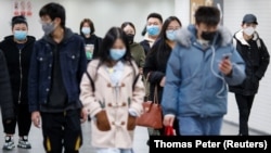 People wearing protective masks in a subway tunnel during evening rush hour in Beijing on March 10.