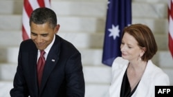 U.S. President Barack Obama signs a guest book as Australian Prime Minister Julia Gillard looks on at Parliament House in Canberra.