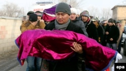 A Kyrgyz man carries the body of a child killed in the crash of a Turkish cargo plane during a funeral ceremony outside Bishkek on January 17.