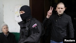 Russian opposition leader Sergei Udaltsov (right) gestures as he is escorted from his apartment after being detained in Moscow on October 17.