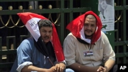 Egyptian protesters cover their heads from the sun with Egyptian flags, as they protest in Tahrir Square in Cairo on July 12, 2011