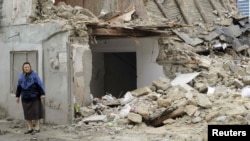 A woman stands near a demolished house in Baku. Critics say the government has trampled on people's rights in razing homes for the Crystal Hall..