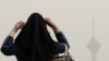 A woman adjusts her head scarf as haze settles over Tehran on July 7.