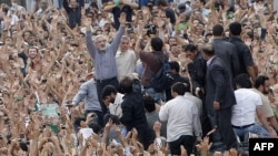 Mir Hossein Musavi (center) raises his arms as he appears at a massive opposition demonstration in Tehran on June 15.