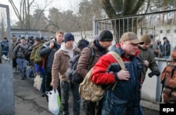 Ukrainian men who were called up for military service according to a mobilization plan walk with their bags in Kyiv before boarding a bus.