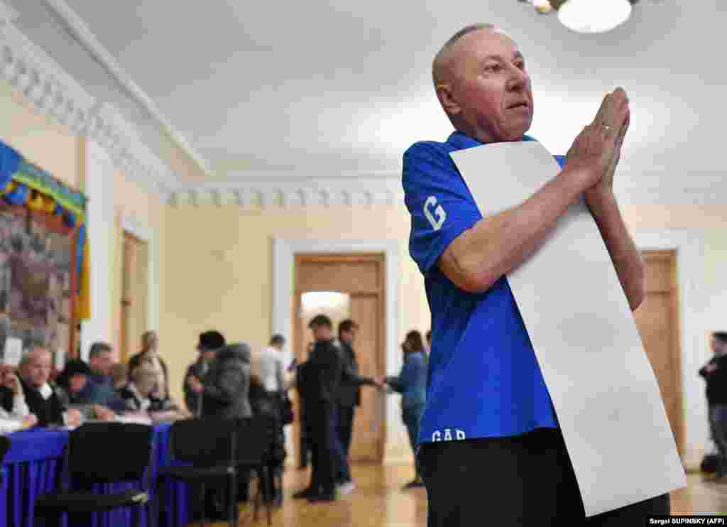 A man prays before casting his ballot at a polling station in Kyiv. (AFP/Sergei Supinsky)