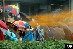 A protester in Minsk makes a defiant gesture as police use a water cannon to disperse an anti-government rally on October 11.