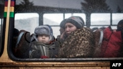 A woman and a young boy sit on a bus as they wait to flee heavy fighting in eastern Ukraine earlier this year.