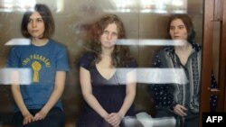 Members of the Russian feminist punk collective Pussy Riot behind a glass cage at their court hearing in Moscow. (Left to right: Nadezhda Tolokonnikova, Maria Alyokhina, and Yekaterina Samutsevich)