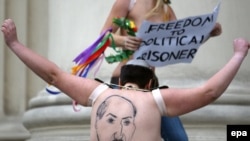 A half-naked Femen activist shows her back, where Belarusian President Alyaksandr Lukashenka is depicted, in front of the KGB headquarters in Minsk on December 19.