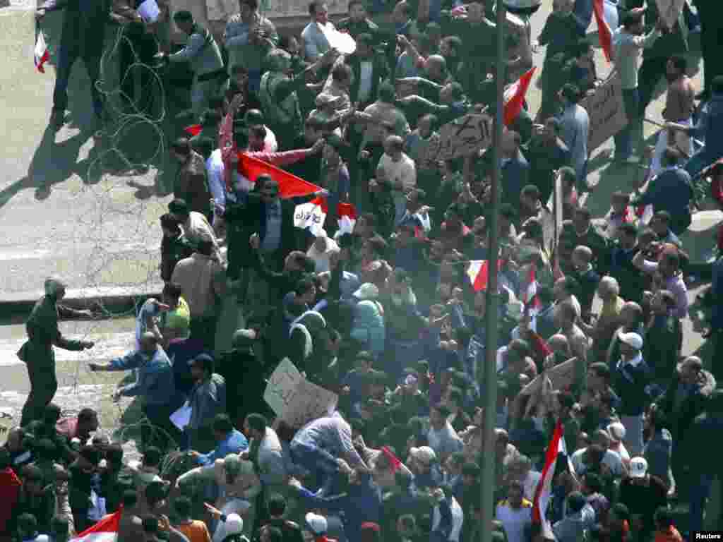 An Egyptian soldier tries to contain thousands of supporters of President Hosni Mubarak pushing into Tahrir Square.