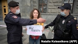 Russian police detain a journalist holding a sign that reads "You are afraid of the truth" near the headquarters of the Federal Security Service in Moscow on August 21.