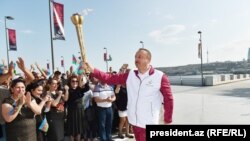 Ilham Aliyev holds the torch carrying the European Games' flame