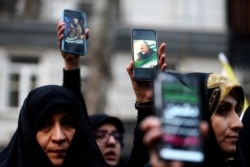 Iranian demonstrators hold up mobile phones showing pictures of Soleimani in Tehran on January 3.