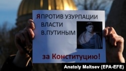 A participant in an unsanctioned rally holds a poster reading: "I am against the usurpation of power by Vladimir Putin, for the constitution!' in front of the Constitutional Court building in St. Petersburg on March 15.