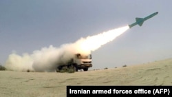 An Iranian missile is fired out to sea from a mobile launch vehicle reportedly on the southern coast of Iran along the Gulf of Oman during a military exercise on June 17.