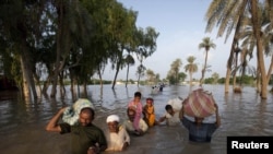 A family wades through flood waters while evacuating Baseera, a village in Punjab Province, where the Kalabagh Dam would be located.