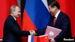 Russian President Vladimir Putin (left) and Chinese counterpart Xi Jinping shake hands after signing an agreement during a bilateral meeting in Shanghai on May 20.