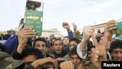 Protesters hold up a destroyed copy of dictator Muammar Qaddafi's "Green Book" as they chant antigovernment slogans in Tobruk on February 22.