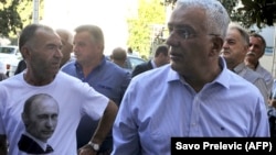 Montenegrin opposition Democratic Front leader Andrija Mandic (right) stands next to a supporter wearing a t-shirt with a picture of Russian President Vladimir Putin before a court hearing in Podgorica on September 6. 