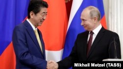 Japanese Prime Minister Shinzo Abe (left) and Russian President Vladimir Putin shake hands after a joint press statement following their meeting at the Kremlin in Moscow on January 22.