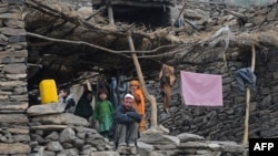 An Afghan family look on from their house in the mountains of Nuristan Province. Locals say Islamist militants have crossed the border from Pakistan and taken over whole districts.