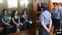 Nadezhda Tolokonnikova (left), Maria Alyokhina (center), and Yekaterina Samutsevich sit inside a glass enclosure during a court hearing in Moscow on August 8.