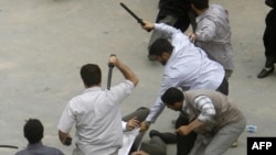 Men in civilian clothes beat a protester during a demonstration on June 14. 