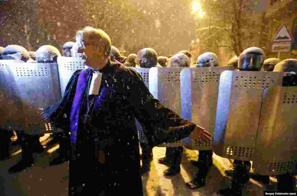 A priest from the St. Elena Lutheran Church attempts to hold protesters back in front of a Kyiv police line.