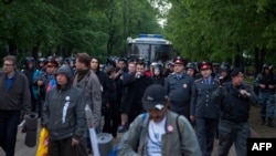 Police officers force away opposition activists from their camp in the Chistye Prudy district in central of Moscow on May 16