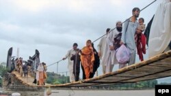 Flood victims cross a temporary bridge as they flee flooded areas of Chakdara, a region in Khyber Pakhtunkhwa Province, on August 6.