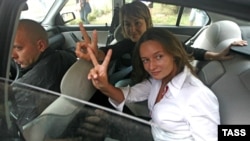 Journalists Irina Kozlik (right) and Yulya Darashkevich show victory signs from a police car after they had been arrested for posing with teddy bears. 