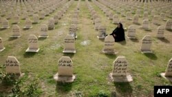 A Kurdish woman visits the graves of her relatives who were killed in the gas attack in 1988 on the 24th anniversary of the attack at the memorial site to the victims in the Iraqi town of Halabja.