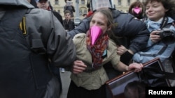 Russian police detain an opposition activist holding a portrait of President Vladimir Putin during a protest on Putin's birthday in Moscow on October 7.