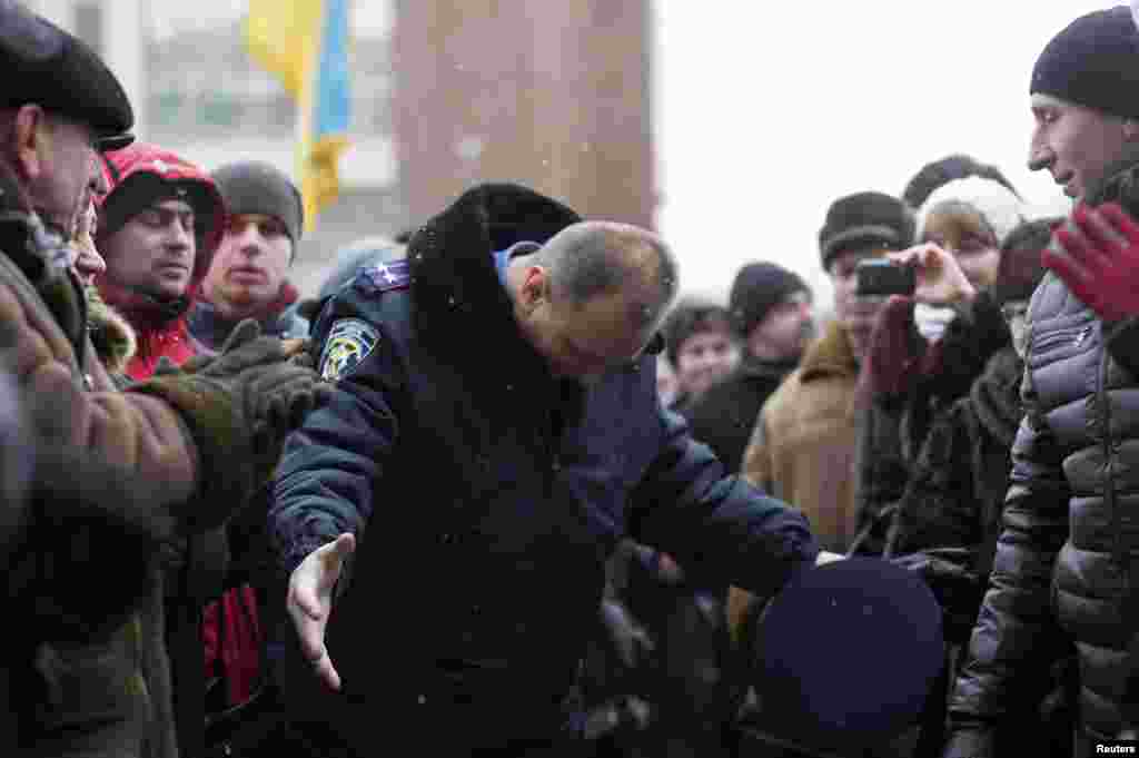 In the town of Ivano-Frankivsk, a&nbsp;police officer bows his head as he leaves the regional administration headquarters, which protesters attempted to take over.