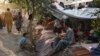 Internally displaced Afghan families who fled fighting between the Taliban and government forces sit in front of their tents in Kabul on August 11.