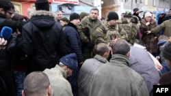 Captured Ukrainian soldiers kneel as the leader of the self-declared Donetsk People's Republic, Aleksandr Zakharchenko (center), stands and members of the media film at a bus stop where up to 13 civilians were killed.