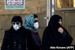 Iranian women wearing face masks wait at a bus stop in Tehran, which has long been plagued by a pollution problem. (file photo)