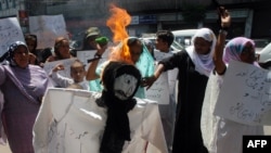 Rights activists torch an effigy of a Taliban member during a protest in Karachi on April 6 against the public flogging of a veiled woman.