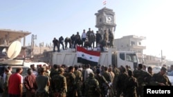 Government soldiers and civilians gather as they place the Syrian national flag on a truck in Qusayr on June 5.