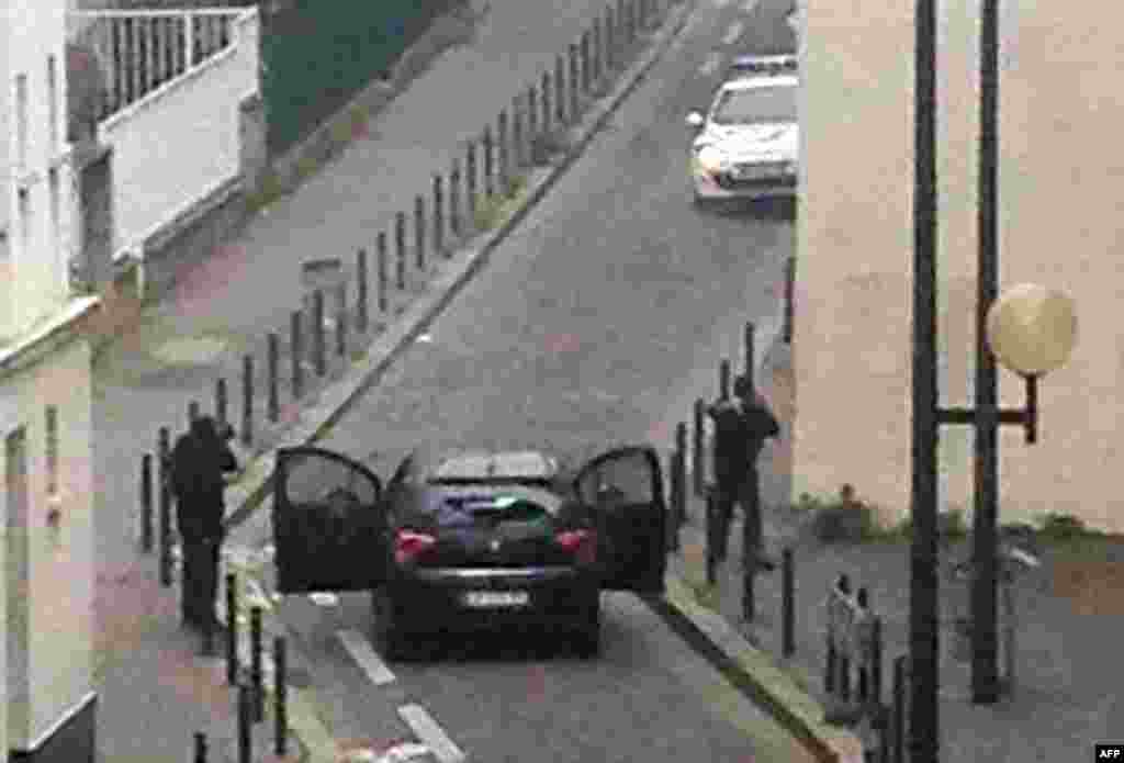 Armed gunmen face police officers near the offices of Charlie Hebdo.