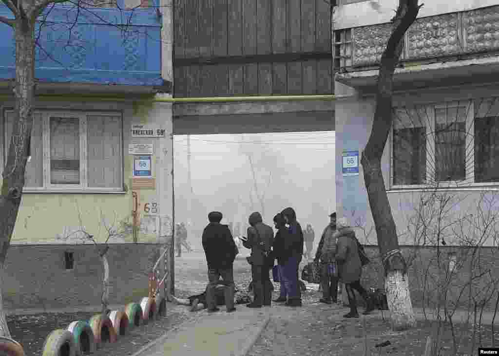 People stand next to the body of a victim.