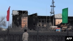 A man stands in front of burned-out official buildings in Zhanaozen on December 18.